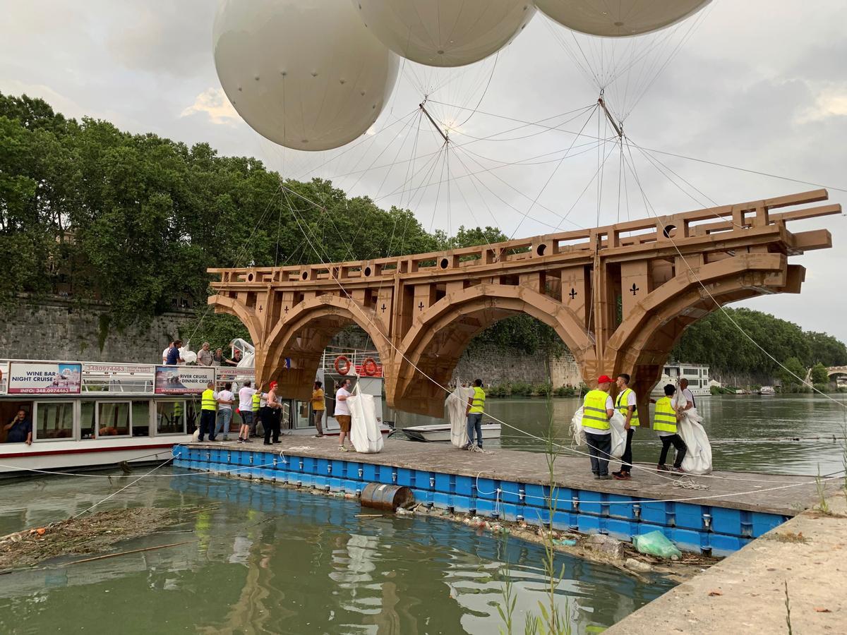 Varios operarios colocan un puente flotador y "efímero" sobre el Tíber en Roma.