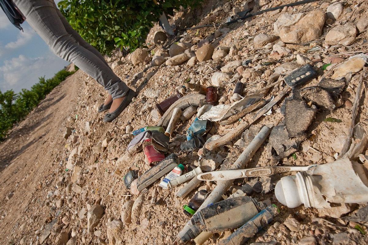 Restos de material sanitario y otros residuos esparcidos en la superficie de un bancal de cítricos cerca de la Rambla Salada de La Murada