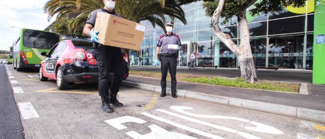 Agentes de la Policía Canaria reparten mascarillas en el transporte urbano durante los meses las crudos de la pandemia.