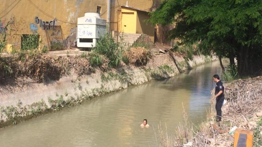 La vecina, en el agua, y un agente al lado.