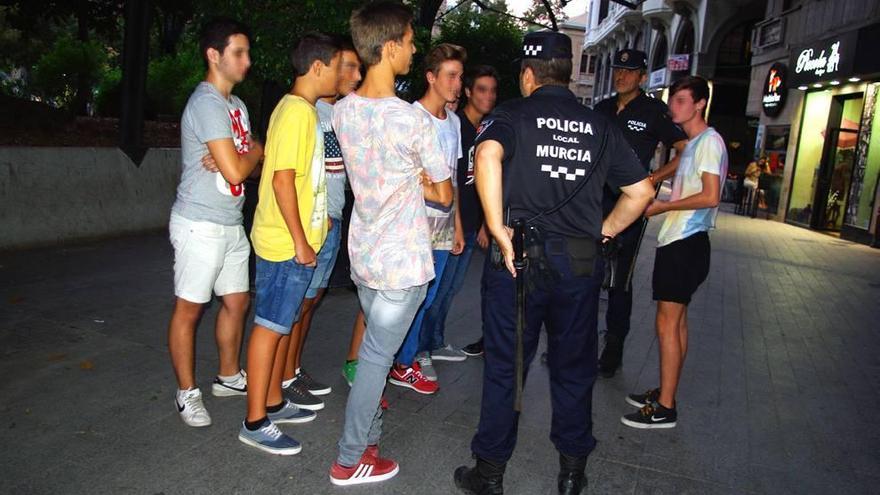 Dos agentes de Policía Local charlan con un grupo de jóvenes en la plaza Santo Domingo de Murcia.