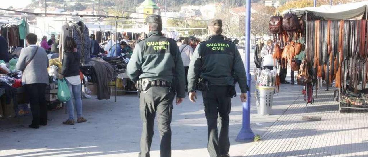 Dos agentes de la Guardia Civil, patrullando por el mercadillo de Cangas. // G.Núñez