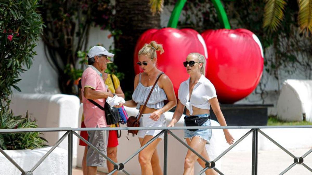 Turistas pasan frente a la discoteca Pacha con el símbolo de las cerezas en la entrada.