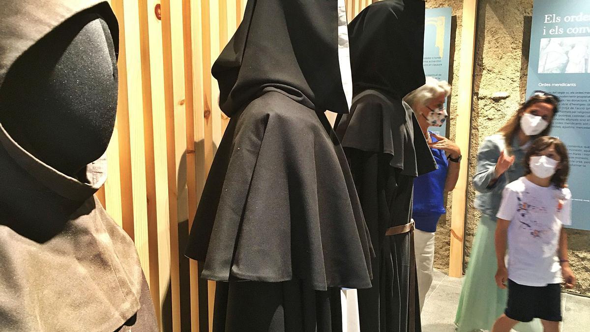 Unes visitants observen els vestits dels ordes dels franciscans, dominics i agustins al nou espai Conventus | MIQUEL SPA
