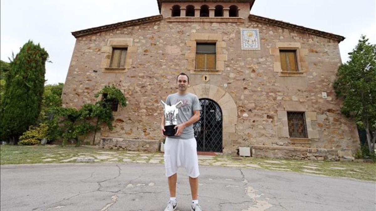 Andrés Iniesta, delante de La Masia, con su trofeo al mejor jugador de la Champions League 2012