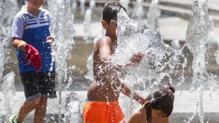 Unos niños se refrescan en una fuente de Alicante.