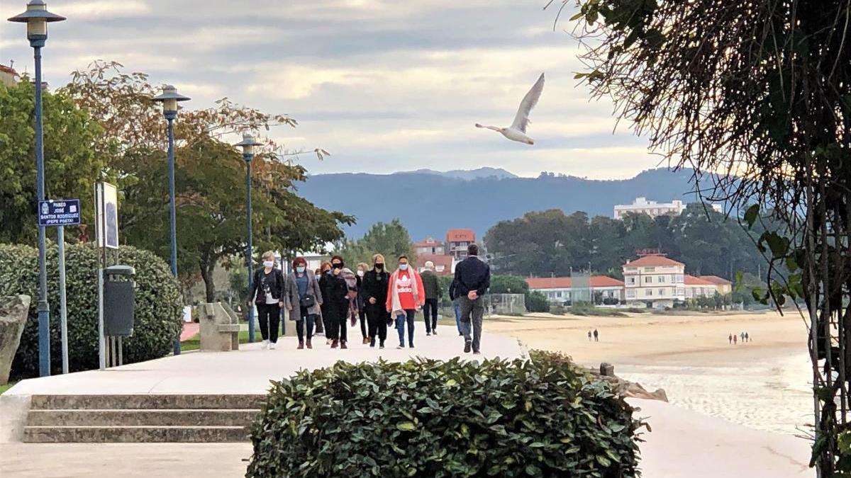 Personas paseando por el frente marítimo de Cangas, este mediodía. // G.M.P.