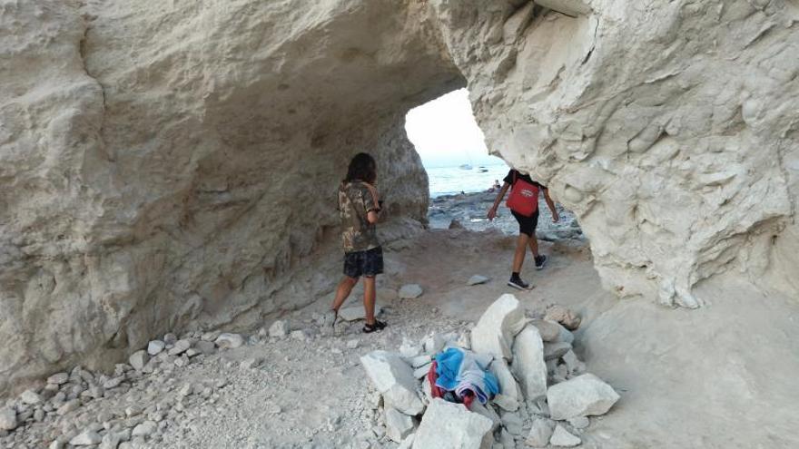 Dos bañistas atraviesan el túnel. A la derecha las rocas desprendidas.