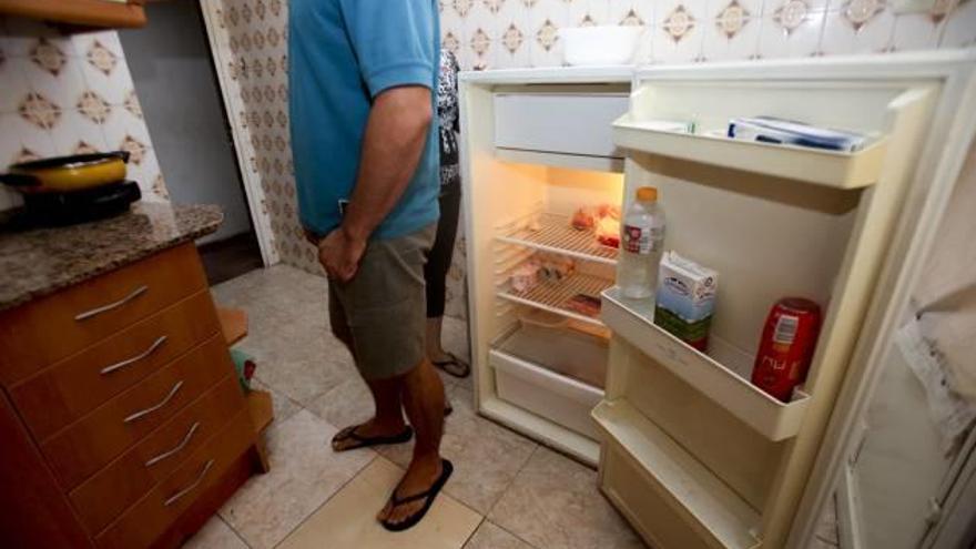 Imagen de archivo de una pareja en la cocina con el frigorífico con los mínimos alimentos.