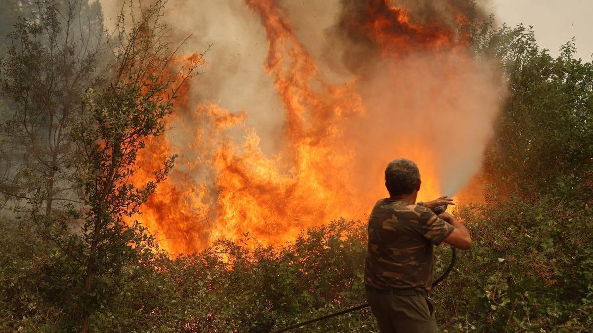 Un vecino lucha contra el fuego en las afueras del pueblo.