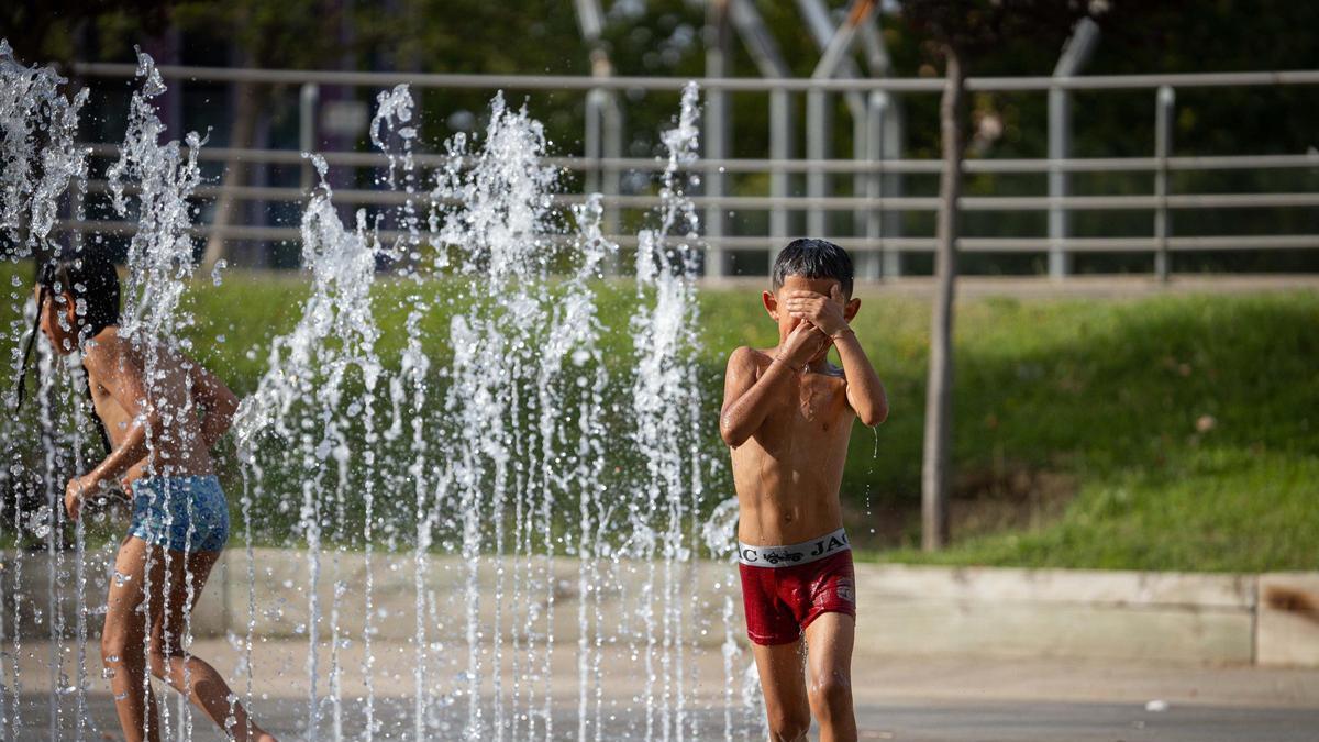 Los niños se refrescan en la fuente de la Expo de Zaragoza ante el calor extremo.