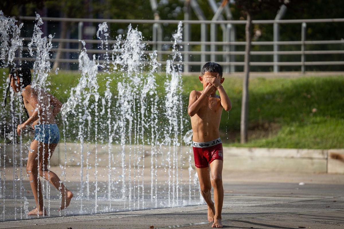 Los niños se refrescan en la fuente de la Expo de Zaragoza ante el calor extremo.