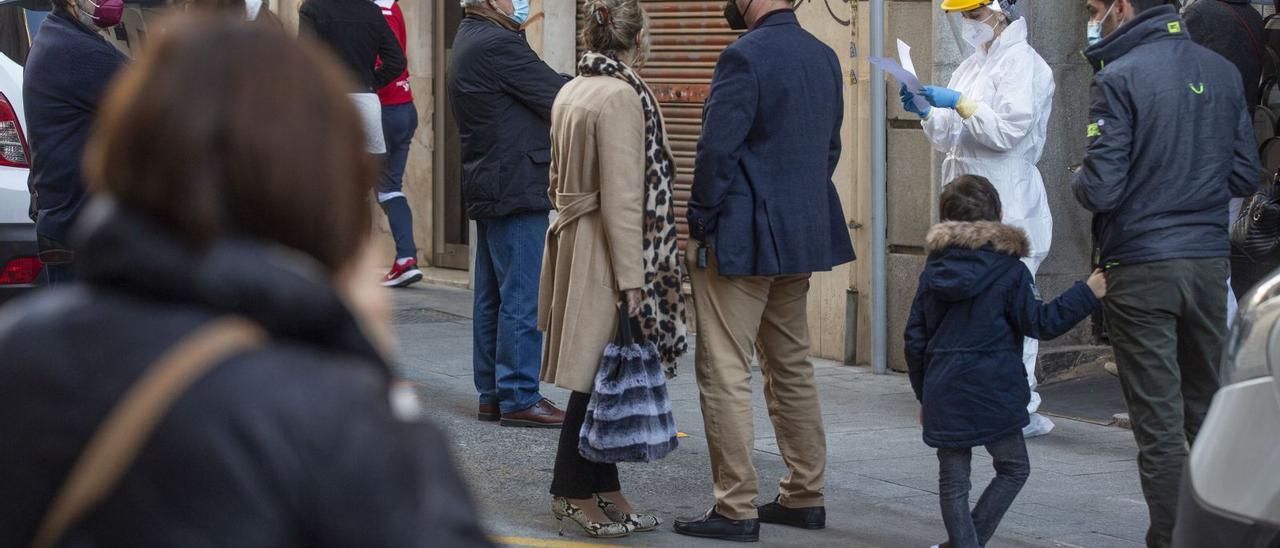 Una sanitaria, enfundada en un EPI, sale a la puerta de un centro de salud de Alicante para llamar a los pacientes. | ALEX DOMÍNGUEZ