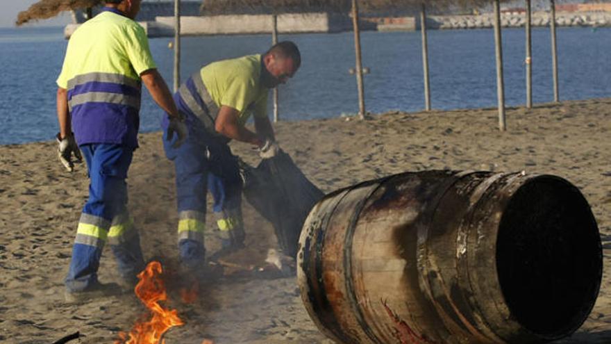 Operarios limpiando una playa tras la noche de San Juan.