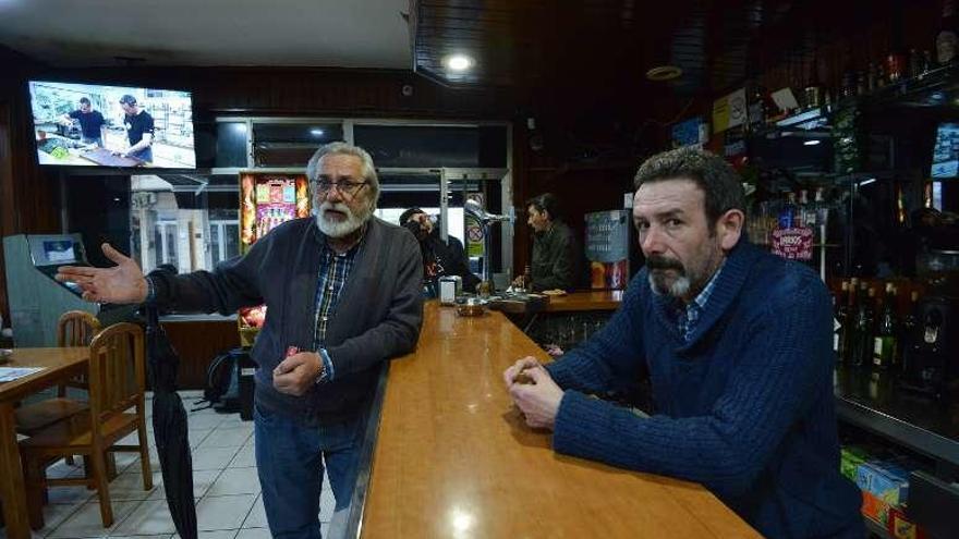 Manolo López charla con un vecino, Jesús Álvarez, en su bar. // G.S.