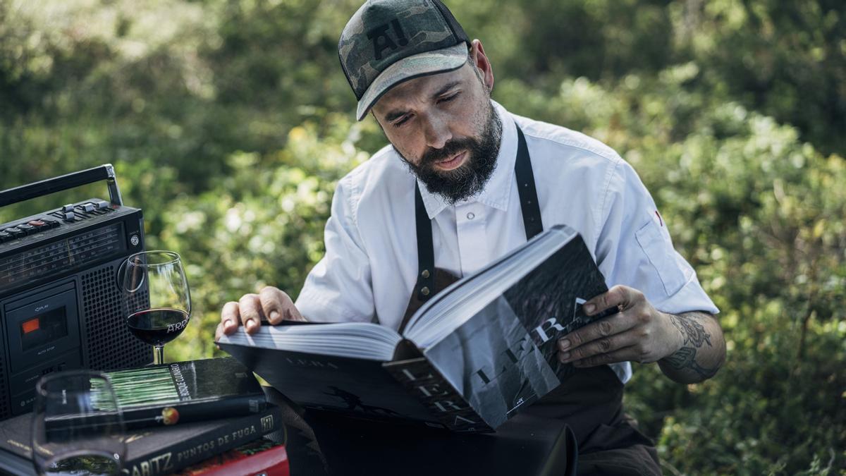 Edorta Lamo, chef del restaurante Arrea!, tomando un vino en uno de los montes alaveses que rodea su establecimiento mientras hojea el libro del restaurante Lera.