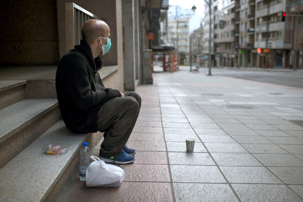 GRAF8292. OURENSE, 17/03/2020.- Un hombre sin hogar con una mascarilla sanitaria permanece sentado en una céntrica calle de Ourense, Galicia, comunidad donde los infectados con coronavirus ascienden a 285. EFE//Brais Lorenzo