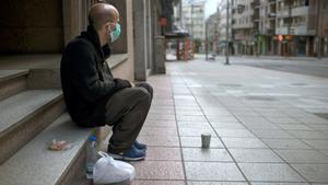 GRAF8292. OURENSE, 17/03/2020.- Un hombre sin hogar con una mascarilla sanitaria permanece sentado en una céntrica calle de Ourense, Galicia, comunidad donde los infectados con coronavirus ascienden a 285. EFE//Brais Lorenzo