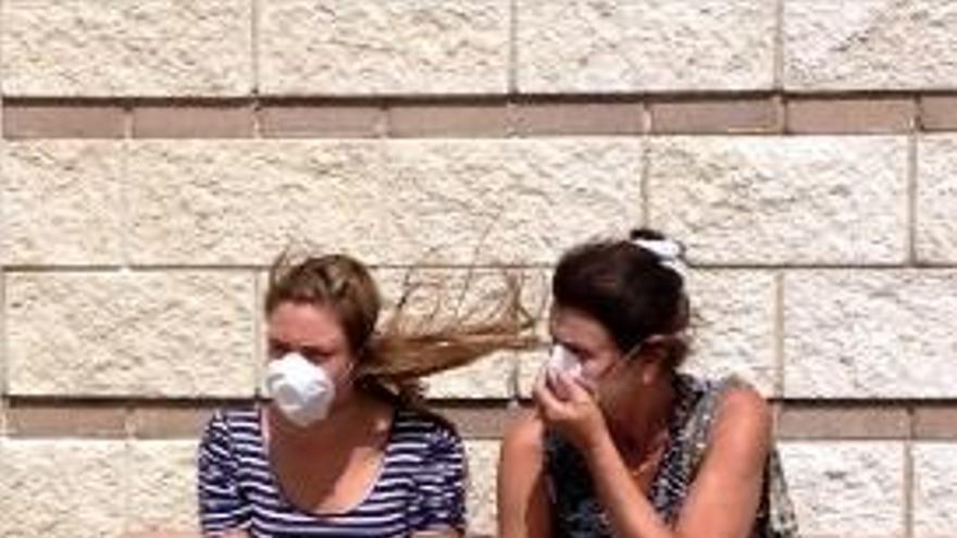 Dues dones tapant-se la cara, en un ambient molt difícil de respirar.