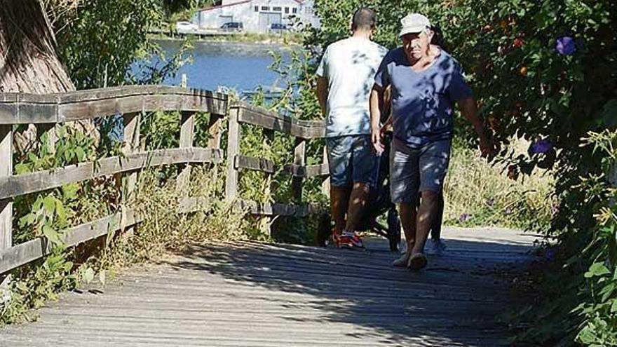 Unas personas pasean por la pasarela de madera de A Portela.  // FdV