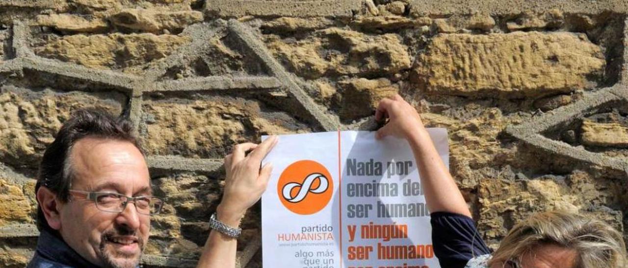 José Antonio López y María Cano, número dos en la lista municipal de Oviedo, colocan un cartel del Partido Humanista.