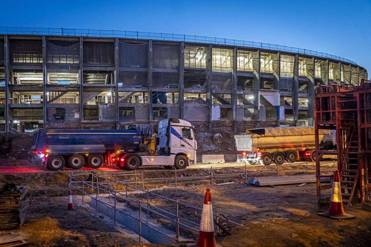 Camiones dentro del recinto en obras del Camp Nou, en Barcelona, al amanecer.