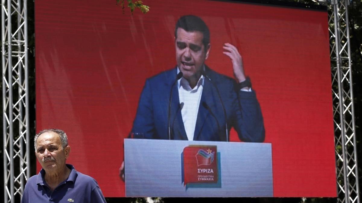 Un hombre pasa frente a una pantalla en la que se proyecta un mitin de Tsipras en Atenas, el pasado 18 de mayo.