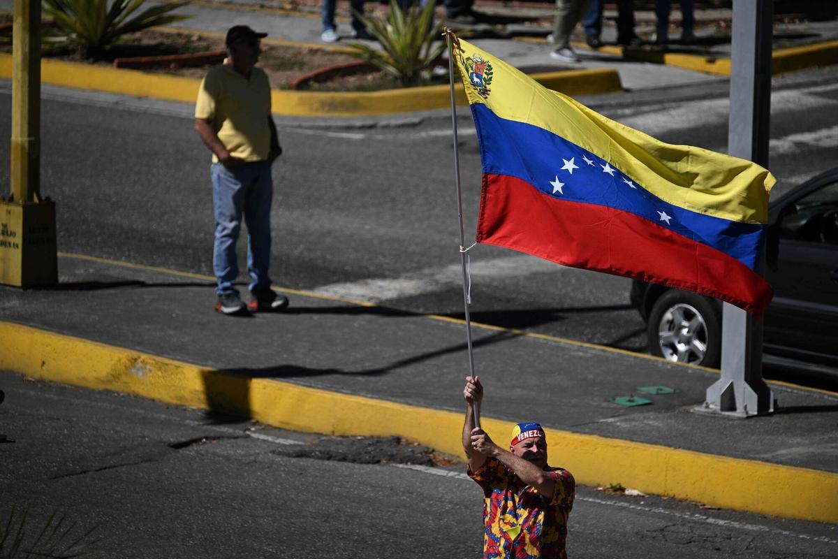 A demonstrator waves a Venezuelan flag during a protest called by the opposition on the eve of the presidential inauguration in Caracas on January 9, 2025. Venezuela is on tenterhooks facing demonstrations called by both the opposition and government supporters a day before President Nicolas Maduro is due to be sworn in for a third consecutive term and despite multiple countries recognizing opposition rival Edmundo Gonzalez Urrutia as the legitimate president-elect following elections past July. (Photo by Federico PARRA / AFP)