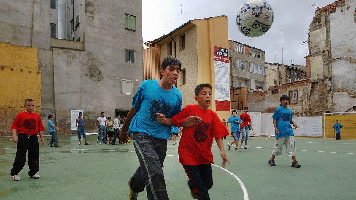 Varios niños jugando a fútbol en la calle.