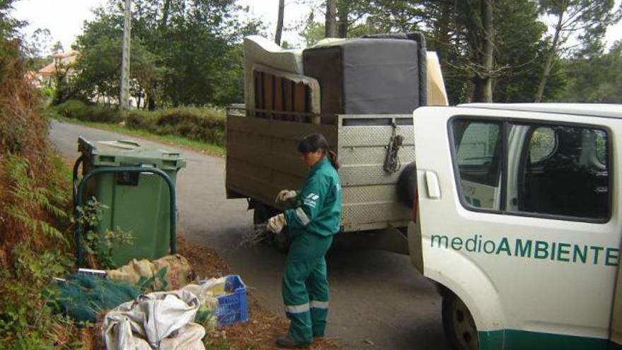 Un operario municipal recoge residuos depositados al lado de un contenedor. / la opinión