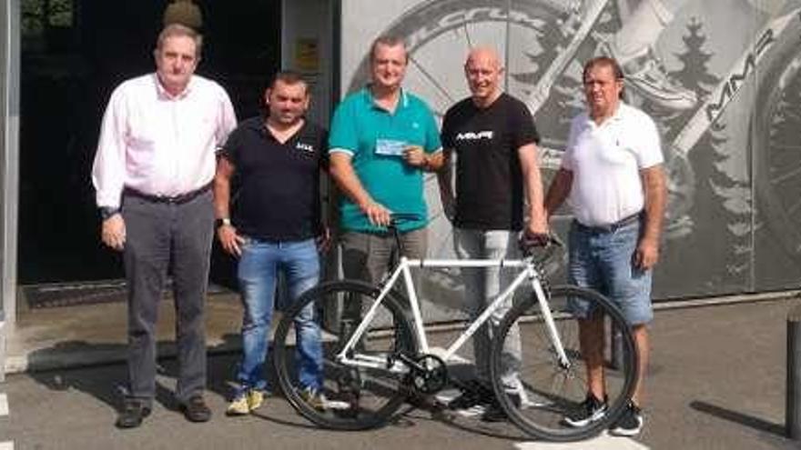 El ganador de la bicicleta, en el centro, recoge su premio en compañía de miembros de la directiva del colectivo organizador.