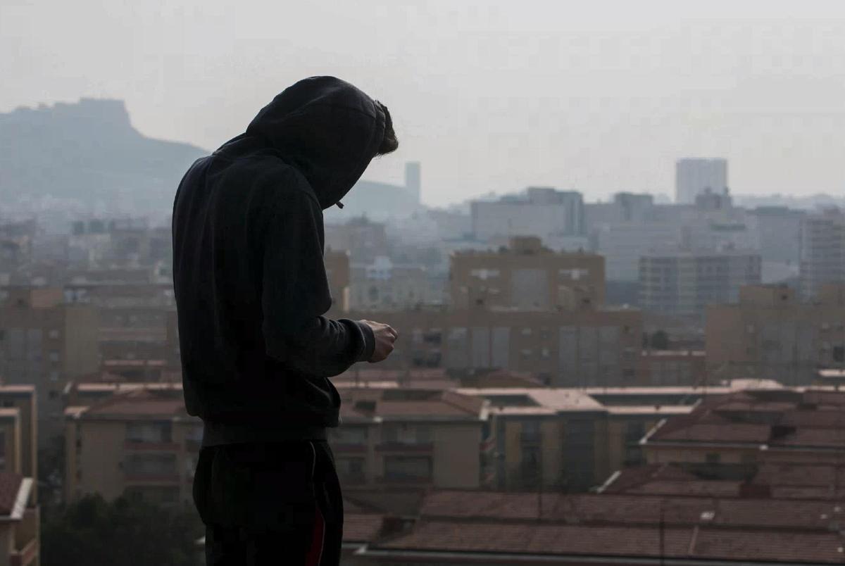 Un joven fumando junto a un centro educativo de Alicante