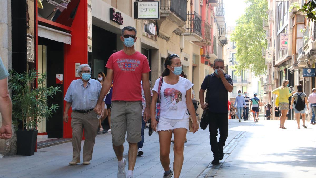 Un grup de persones davant de les botigues de Figueres durant l&#039;estiu