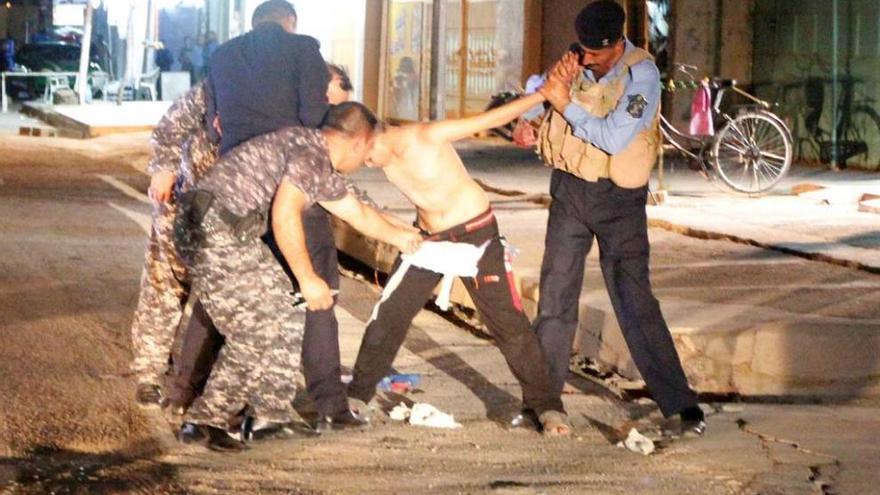 Fuerzas de seguridad iraquíes retiran del cuerpo de un niño un cinturón con explosivos.