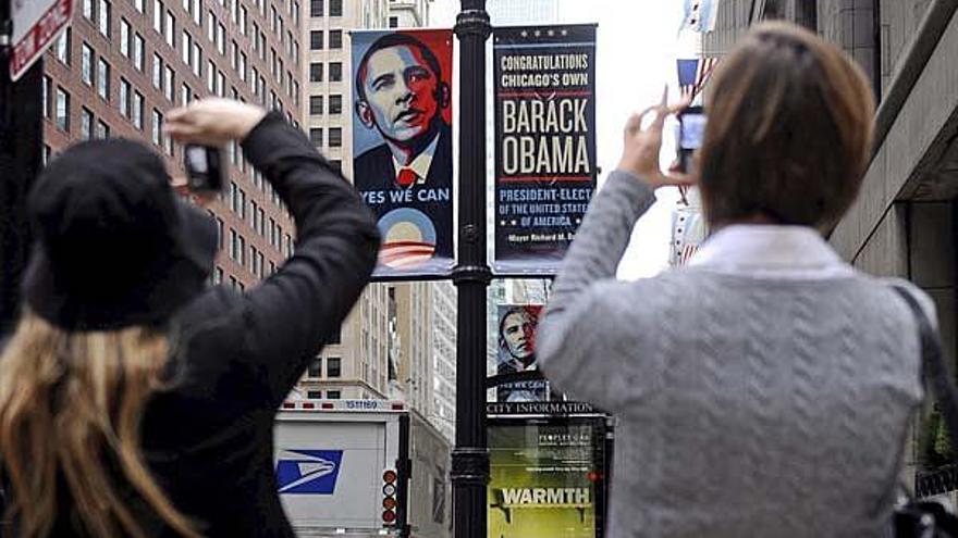 Unas mujeres toman fotografías a una pancarta con la imagen del presidente electo