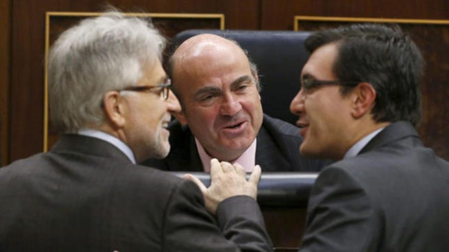 El ministro de Economía, Luis de Guindos (c), habla con el diputado de CiU Josep Sánchez Llibre (i) y con el popular José Luis Ayllón.