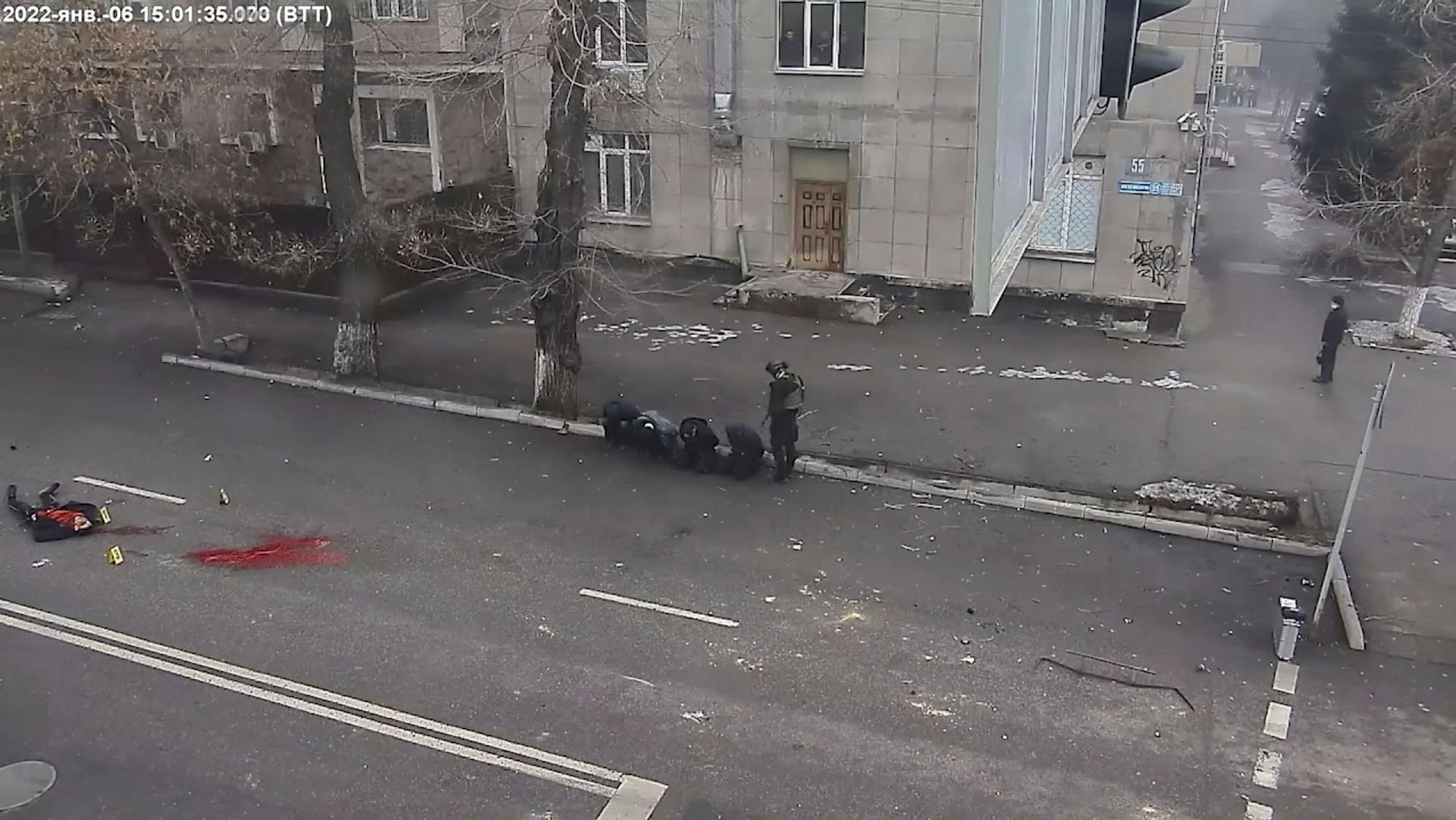 Un cuerpo yace en el suelo junto a un charco de sangre mientras un oficial kazajo apunta contra cuatro arrestados, en un vídeo difundido por el Ministerio del Interior de Kazajistán este jueves.