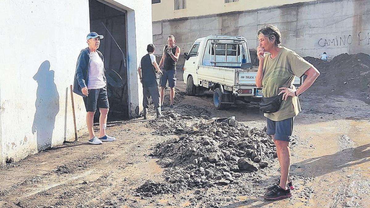 Varios vecinos del mismo barrio sacan lodo y enseres de una de las casas anegadas.