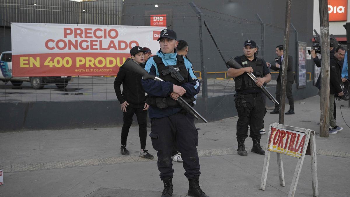 Agentes de policía montan guardia a las puertas de un supermercado saqueado en un suburbio de Buenos Aires.