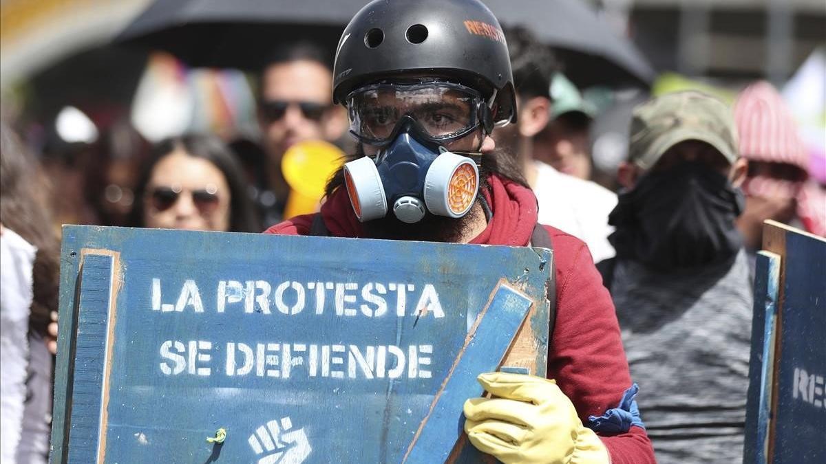 Una manifestante sostiene un cartel de protesta en una marcha en Bogotá contra el Gobierno de Duque.