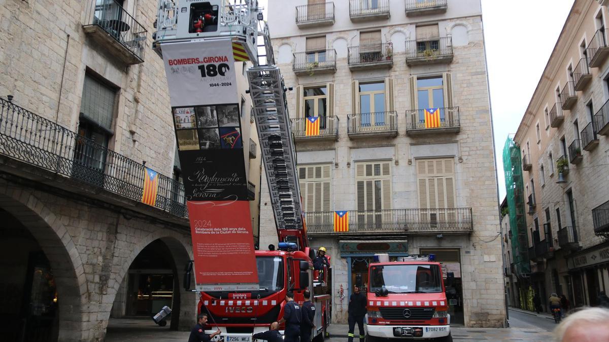 L'autoescala dels Bombers de Girona amb la pancarta en motiu dels 180 anys del cos