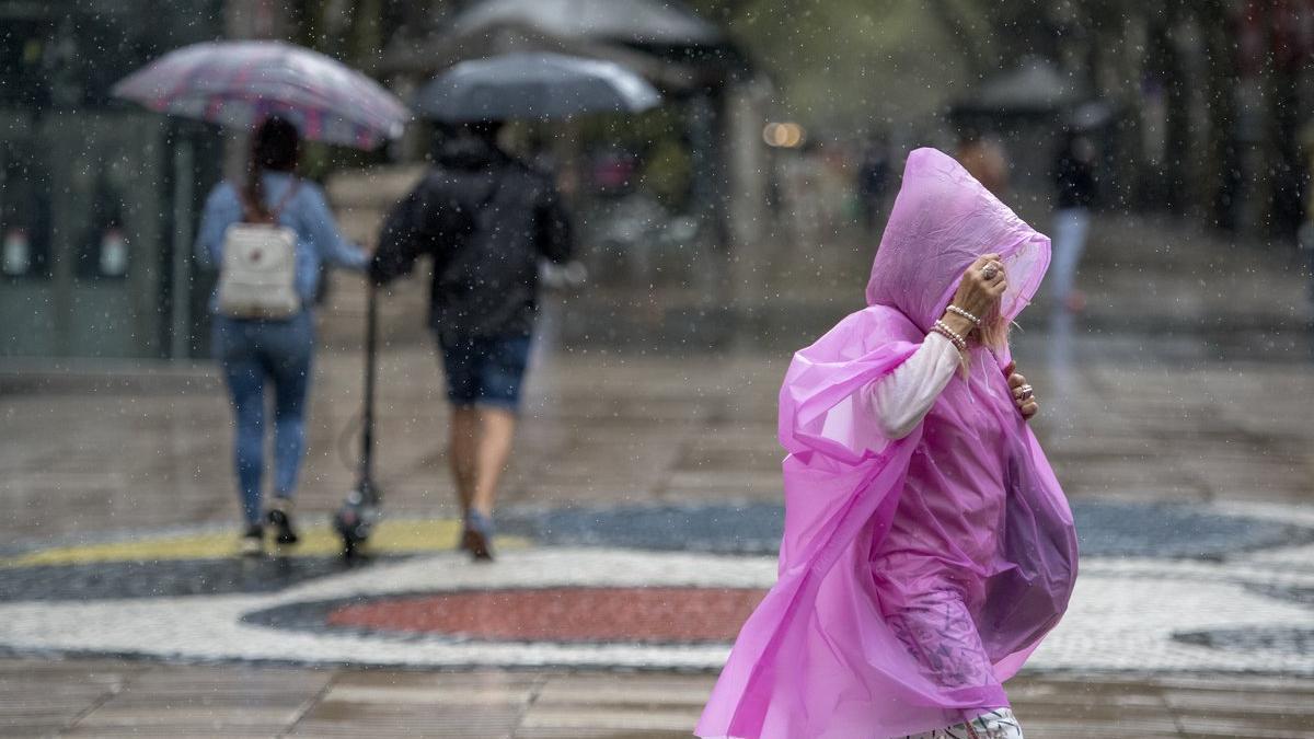 Varias personas se protegen de la lluvia, en las Ramblas de Barcelona.