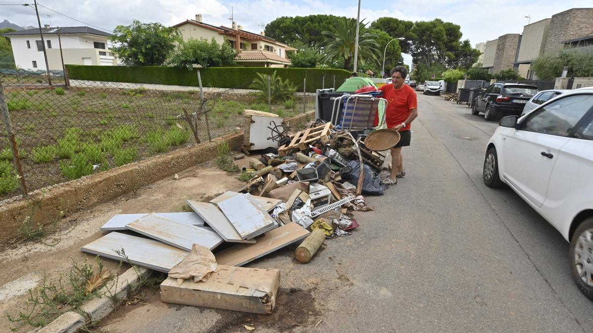 Un vecino tira una paella y una silla de playa a un vertedero improvisado lleno de enseres inutilizados por la lluvia en la calle Florida.