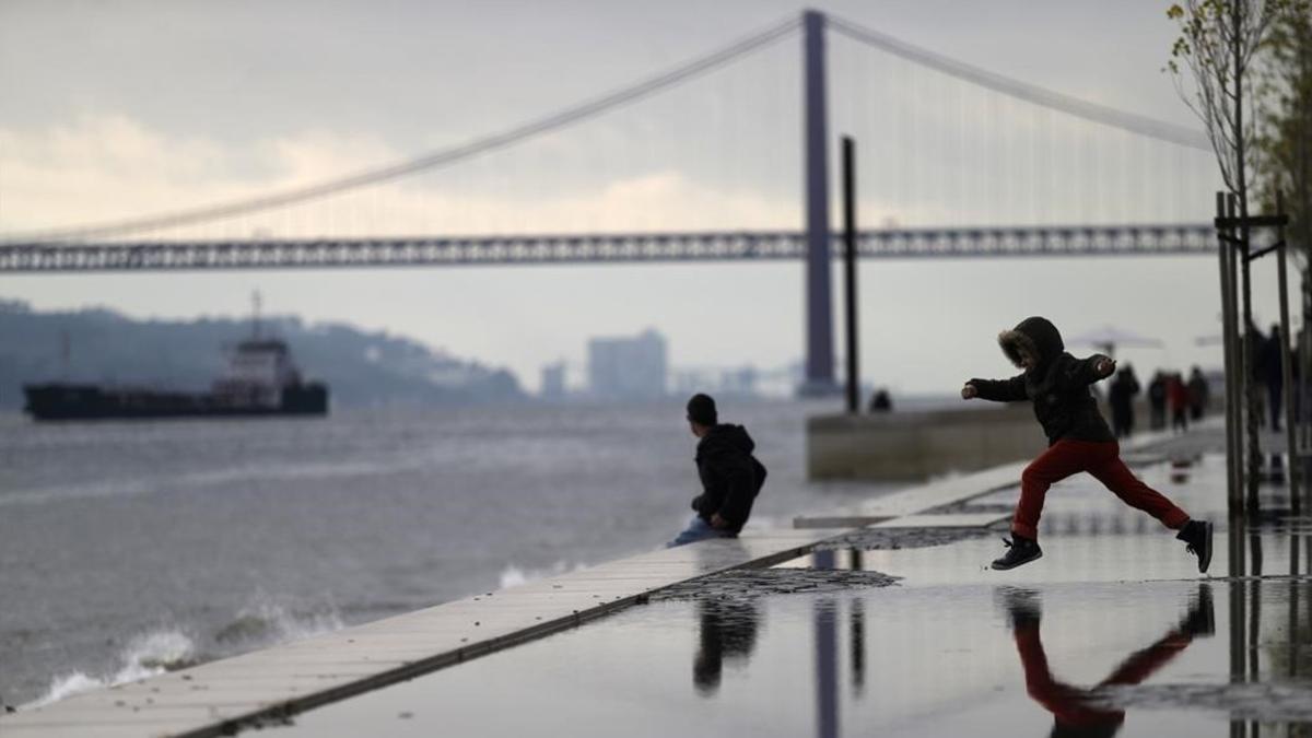 Un niño corre frente al puente 25 Abril en Lisboa.