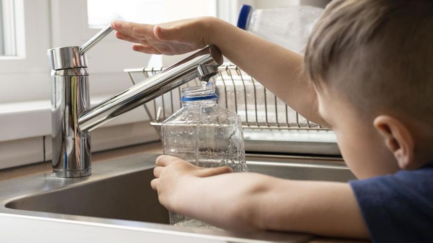 Un niño rellena una botella de plástico con agua potable del grifo. | FREEPICK