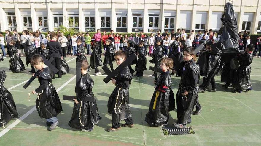 Un grupo de niños procesiona en el patio del colegio.