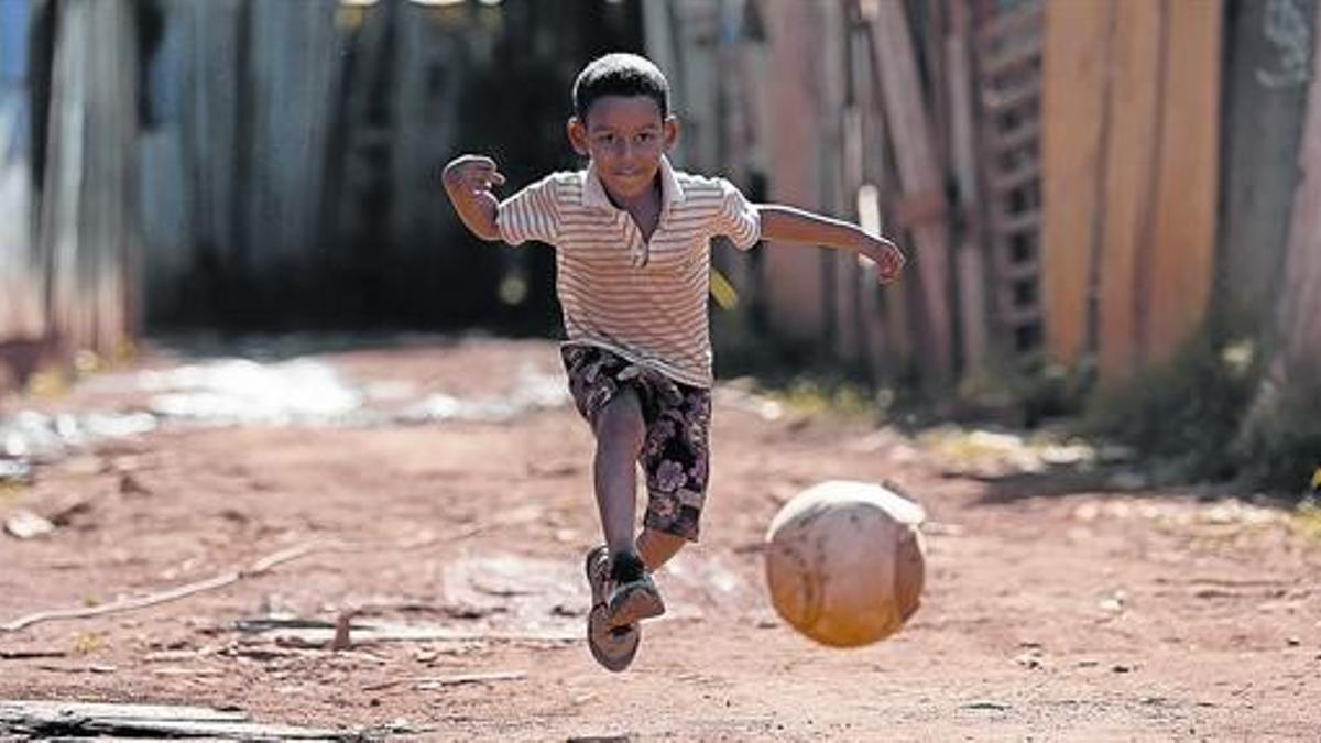 Un niño juega con un balón en la favela de Santa Luzia, en Brasilia.