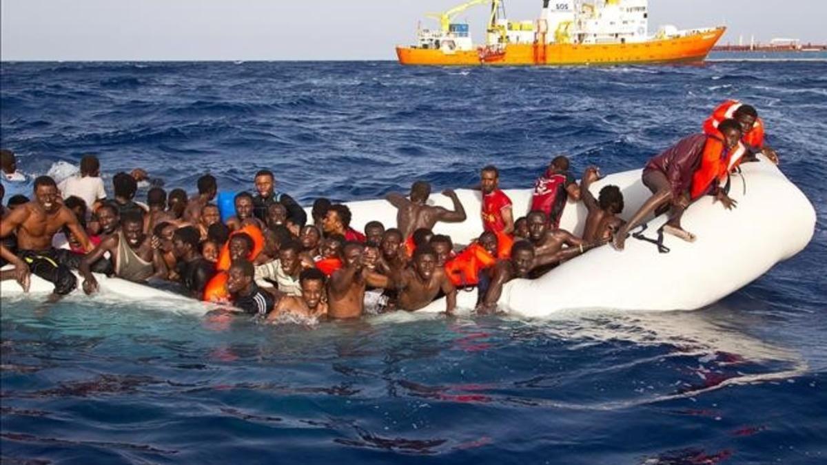 Momento en que varios inmigrantes son rescatados el lunes en alta mar cerca de la costa italiana.