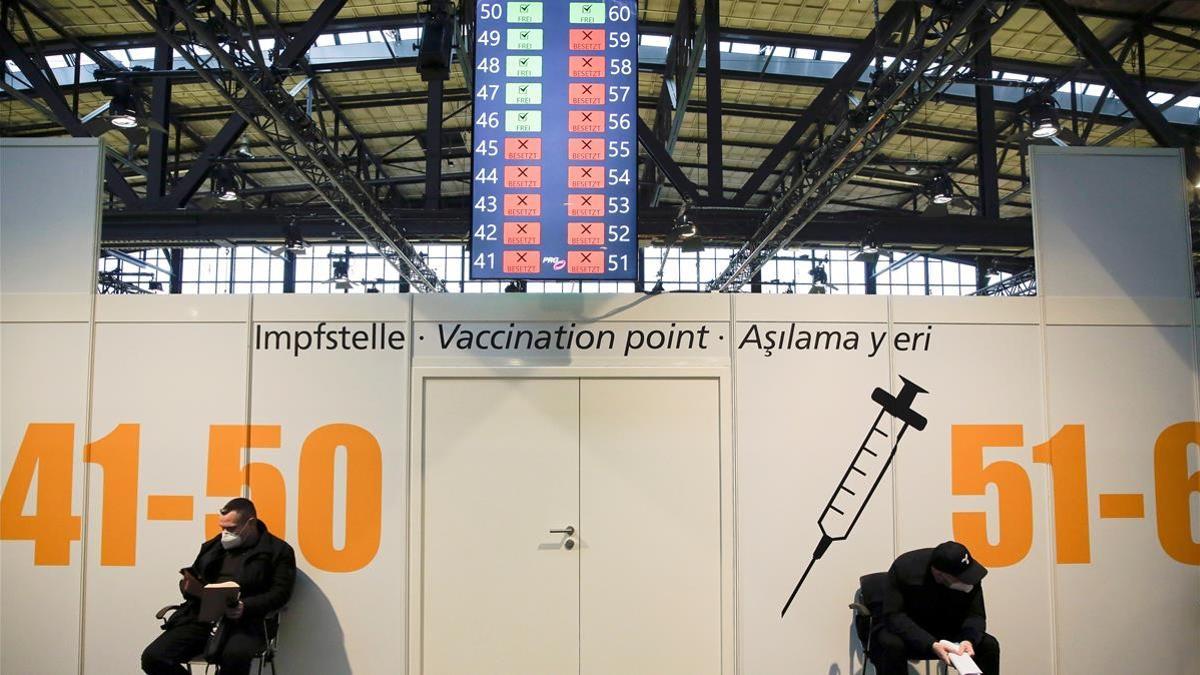 Dos hombres esperan su turno para ser vacunados en el centro de vacunación Treptow Arena de Berlín, el 27 de diciembre de 2020