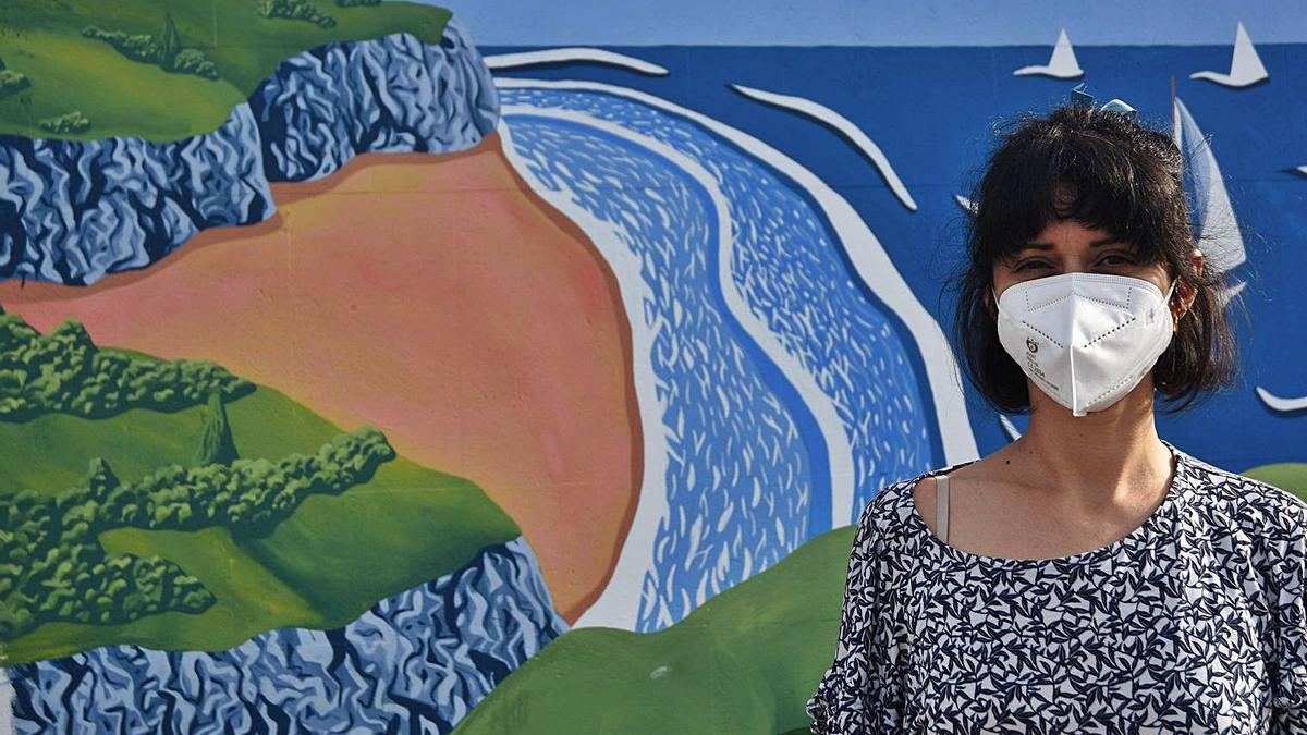 Helena Toraño, delante de su mural en la pared lateral de la Escuela de Vela del espigón central de Fomento. |  EFRÉN TOMÁS